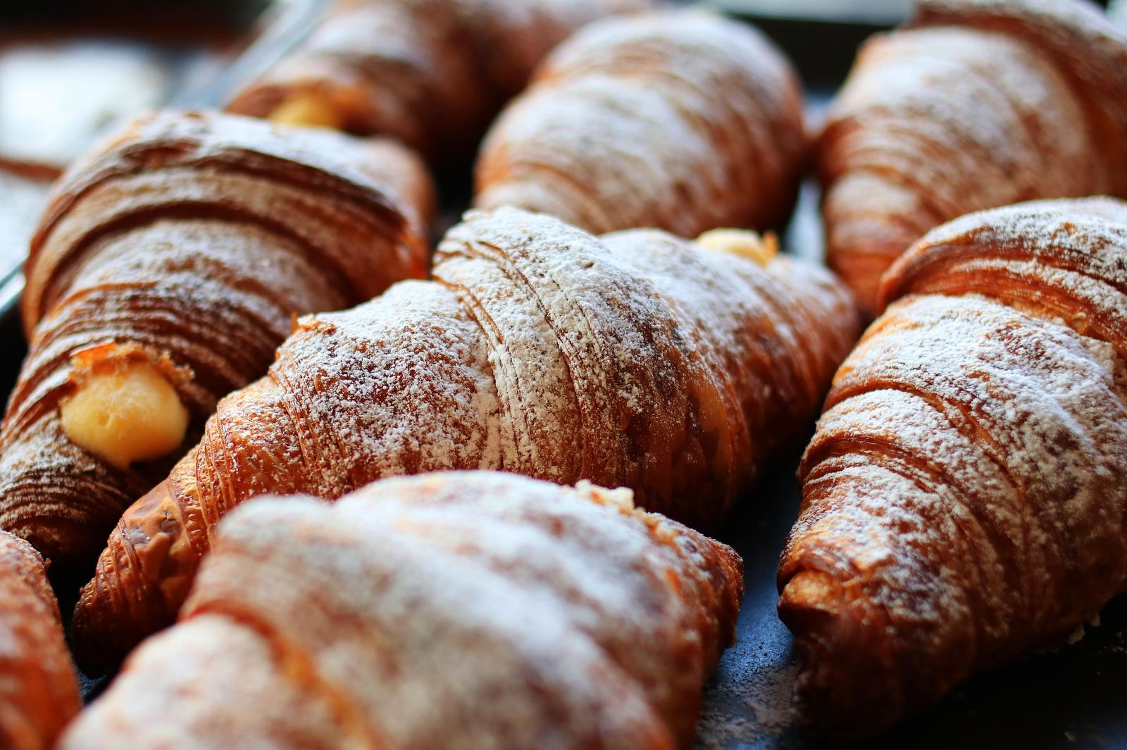 Viennoiseries et croissants tout juste sortis du four, saupoudrés de sucre glace